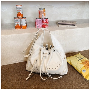 Detail view of white punk style bucket bag with metal rivets and long fringe tassels