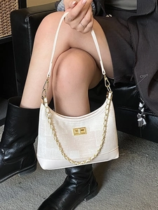 White woven crossbody bag with gold chain strap and lock buckle shown on model