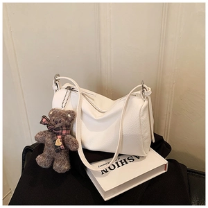 White lychee pattern shoulder bag with a brown teddy bear charm on fashion book