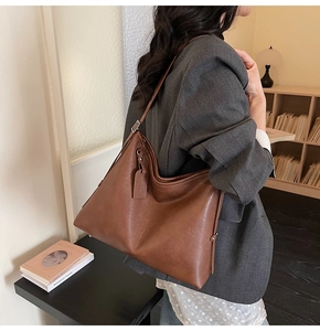 Détail d'un sac cabas en cuir vintage marron vu de l'épaule d'un mannequin en situation