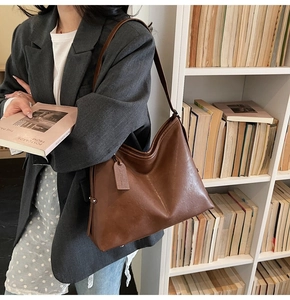 Détail du sac à bandoulière en cuir marron avec étiquette vintage et rivets métalliques