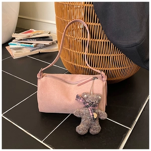 Detail of pink suede pillow bag with soft plush bear pendant in an indoor setting
