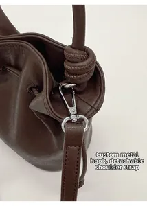 Detail of silver hardware hooks and detachable strap on the brown leather bucket bag