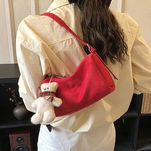 Red suede hobo bag shown on shoulder with cute plush bear charm and love heart detail