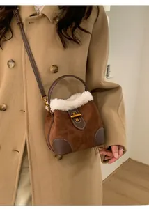 Sac seau en daim marron avec bordure en fausse fourrure blanche porté sur un manteau kaki