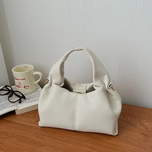 Detail of off-white ruched handbag with lychee texture and gold-tone metal hardware