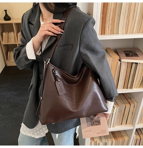 Vue détaillée du cabas en cuir marron foncé au fini brillant avec étiquette logo