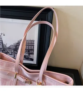 Detalle de tela jacquard rosa y asas de cuero con elegantes detalles metálicos dorados