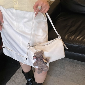 Detailed macro of white litchi grain leather pillow bag with cute plush bear charm