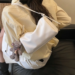 Detail of white pebble grain pillow bag featuring a cute teddy bear charm accessory