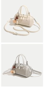 Detail view of beige canvas Boston bag with plush bear charm and dual zip closure