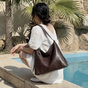 Grand sac à bandoulière en cuir marron minimaliste dans un décor de villégiature