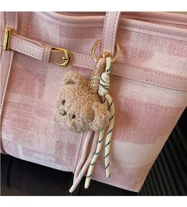 Detalle del bolso tote rosa geométrico con hebilla dorada y amuleto de osito peluche