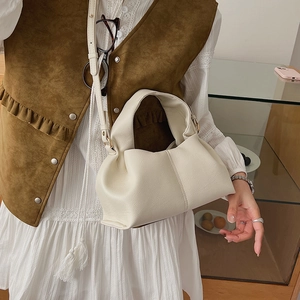 Detailed view of a white lychee grain leather cloud bag with gold-tone hardware and strap