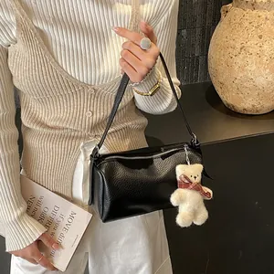 Detail of black pebbled leather pillow bag with silver zipper and cute teddy bear charm