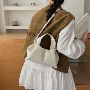 Chic cream cloud handbag with soft leather pleats shown on a model in a cozy interior