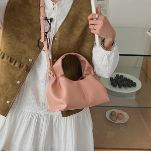 Pink pleated cloud handbag with soft leather texture shown in a lifestyle model shot