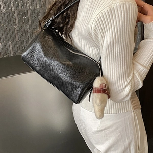 Detail of black pebbled leather cylinder bag with silver zipper and cute bear pendant