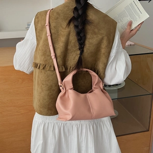 Pink cloud-shaped pleated bag shown in use with adjustable crossbody shoulder strap
