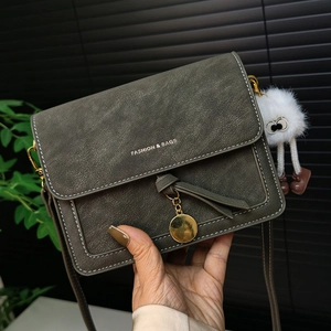 Dark green litchi texture crossbody bag with white stitching and plush monster charm