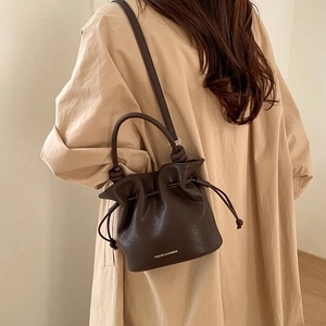 Detail view of the drawstring closure and premium brown leather texture of the bucket bag