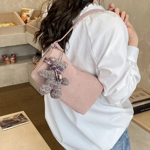 Pink shoulder bag detail showing a plush bear charm and matte synthetic leather finish