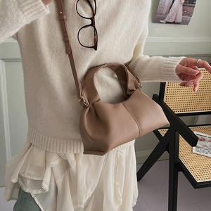 Detailed texture of brown pleated leather crossbody bag with adjustable strap