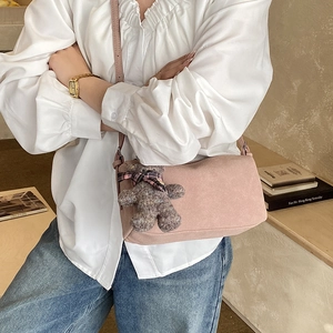 Detail of pink faux suede pillow bag with a cute plush bear pendant and thin shoulder strap
