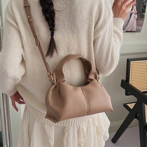 Detail of soft khaki cloud bag with ruched leather and adjustable strap on a model