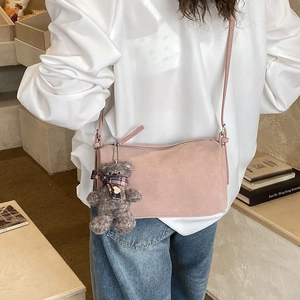 Detailed shot of pink suede pillow bag with cute plush bear charm on adjustable strap