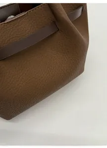 Detail einer braunen Eimer-Tasche aus Leder mit Litschi-Muster und feinen Nähten