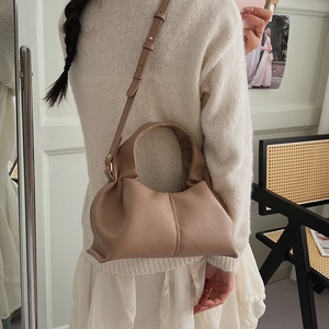 Detail of French-style cloud bag showing litchi grain leather and gold strap buckle