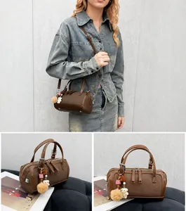 Close-up of brown Boston bag showing dual zippers and cute bear plush charm accessory