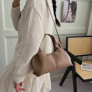 Detail showing the lychee grain leather texture and elegant pleats of the light brown cloud bag