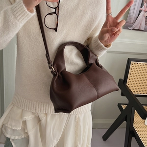 Detail of dark brown lychee leather handbag with cloud shape and adjustable strap