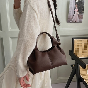 Detail of dark brown lychee texture leather handbag on model in elegant setting