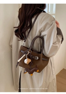 Detail der dunkelbraunen Leder-Eimertasche mit Dackel- und Baseball-Anhängern