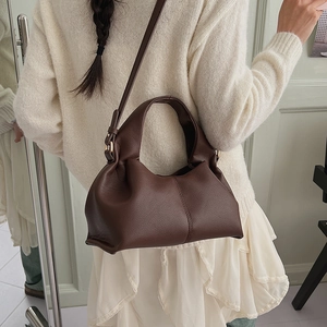 Close-up of dark brown leather cloud bag with pleated handle and gold hardware detail