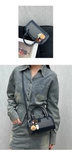 Detail of grey woven Boston bag with navy leather trim and playful charm accessories