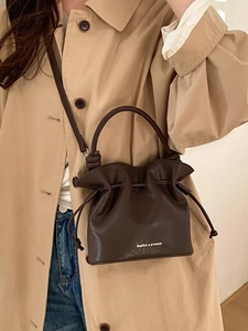Minimalist dark brown drawstring bucket bag with logo for versatile crossbody wear