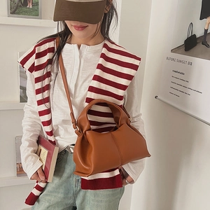Close-up of caramel brown leather cloud bag with ruched design and slim shoulder strap