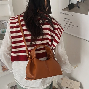 Detail view of caramel brown pleated cloud bag with adjustable shoulder strap and handle