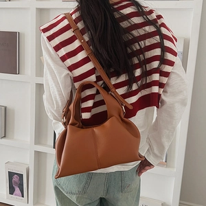 Brown lychee leather hobo bag worn over shoulder by a model in a casual setting