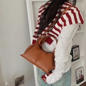 Detail of caramel brown faux leather cloud bag worn by model with minimalist styling