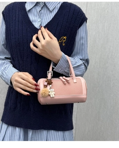 Pink cylinder boston bag with a plush bear charm and metallic hardware details
