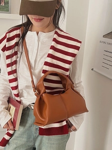 Fashionable caramel leather dumpling cloud handbag worn by a model in a natural setting