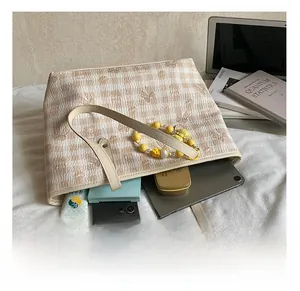 Detail view of large checkered tote bag showing spacious interior with books and tablet