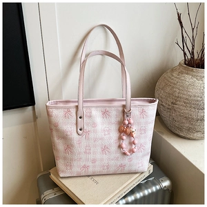 Detail of pink tote bag featuring cartoon patterns and a decorative beaded charm