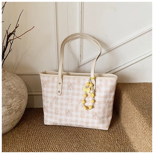 Close-up of beige checkered tote bag with cute bear prints and yellow beaded charm