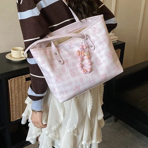 Detail of pink tote bag featuring embossed cartoon patterns and floral beaded charm